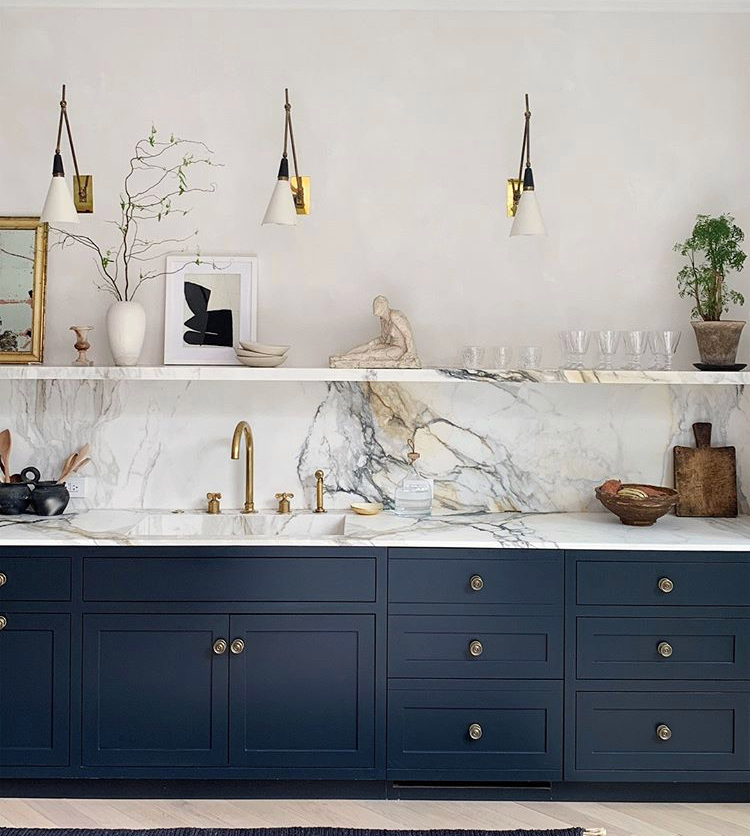 navy and white kitchen with marble backsplash and shelf