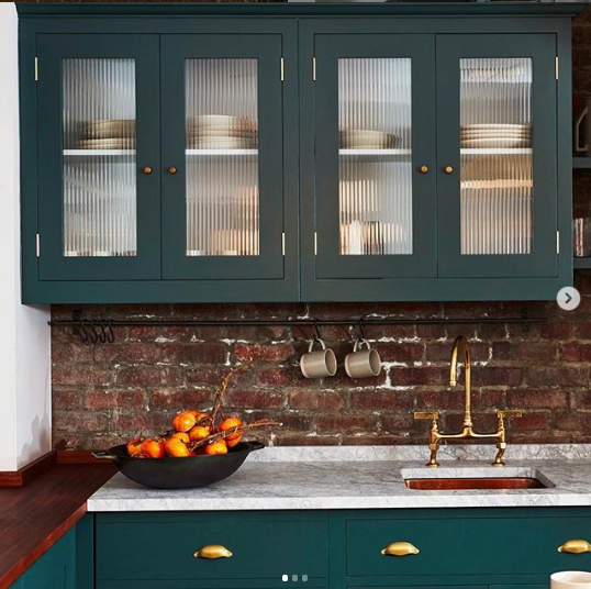 green kitchen cabinets with brick backsplash