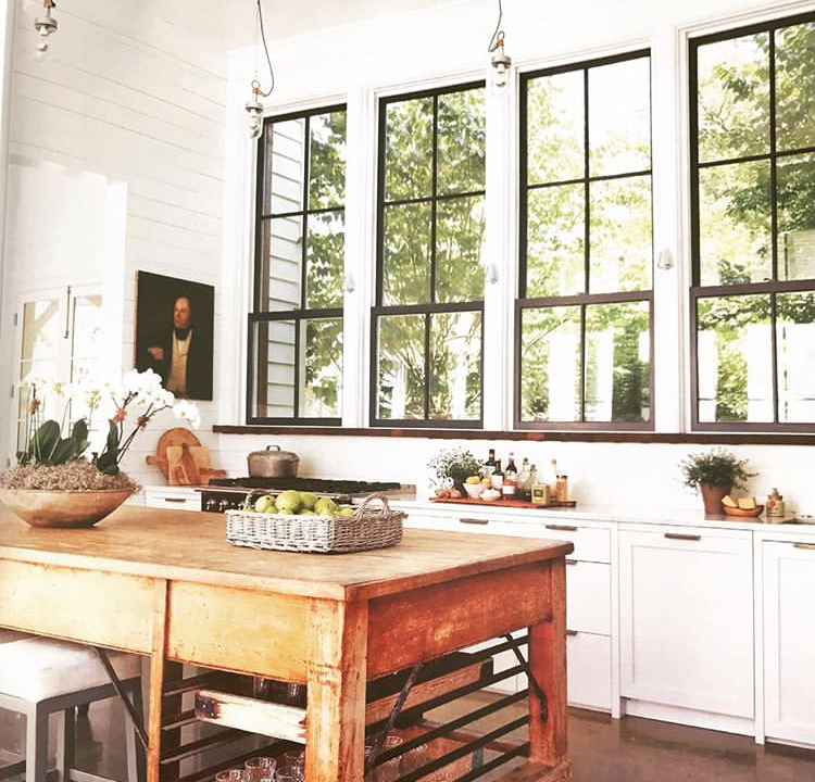 wood movable island in kitchen with large windows