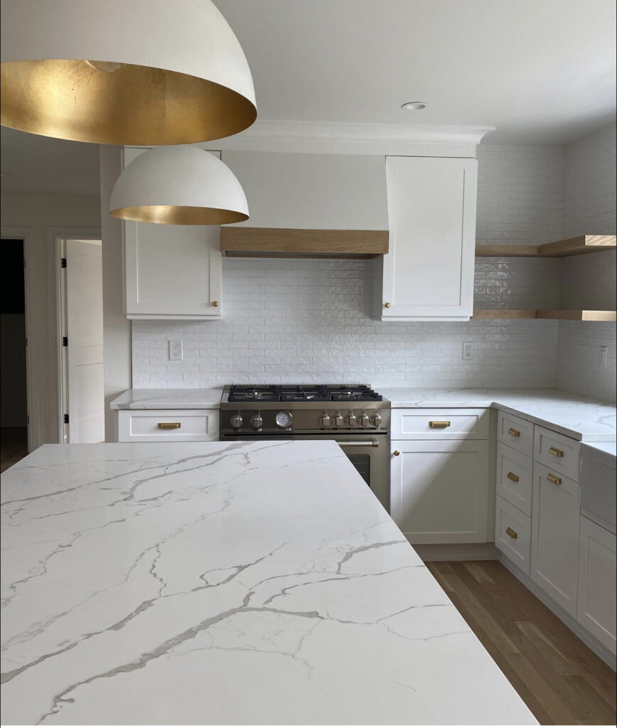 white kitchen with white range hood and gold and white pendants