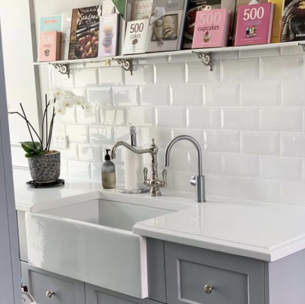 white farmhouse sink with shelf and books above