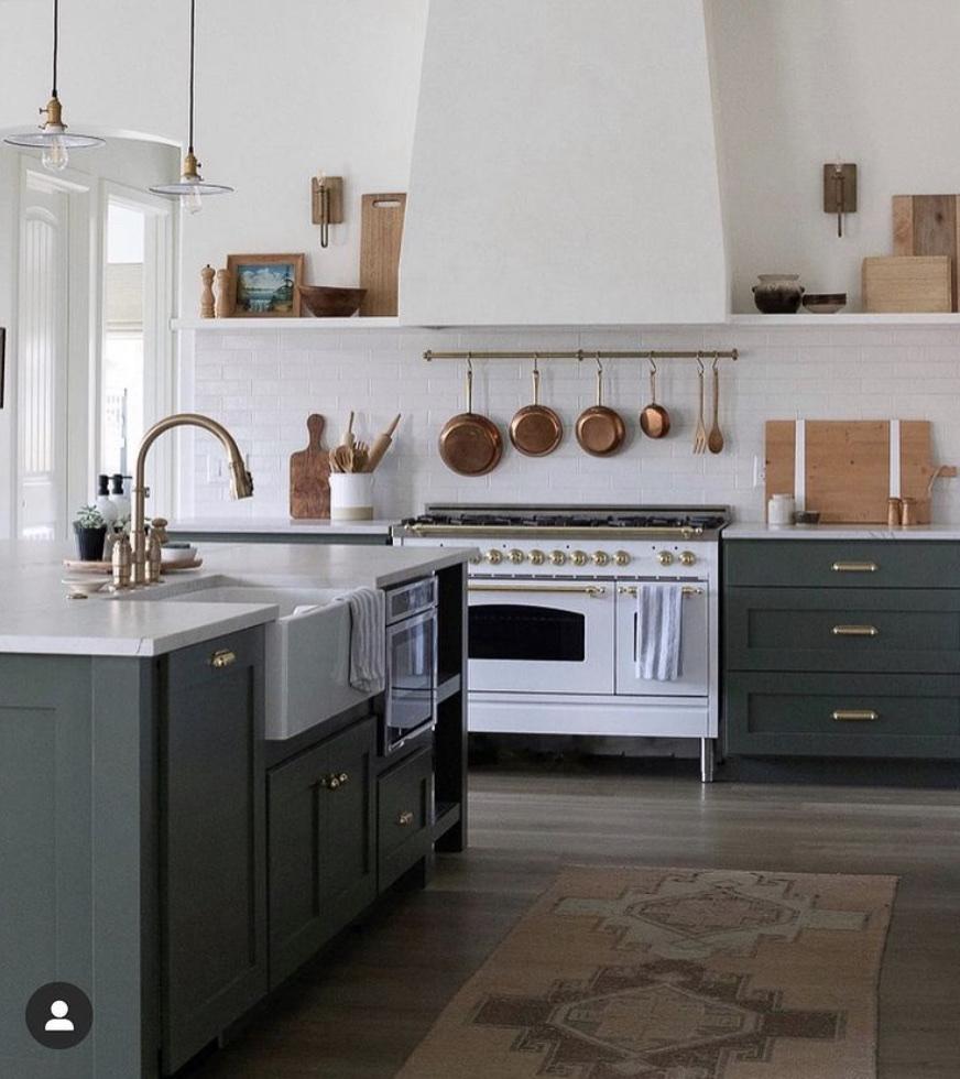 green and white kitchen with copper pots and pans