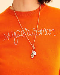 orange sweater with superwoman embroidered on it