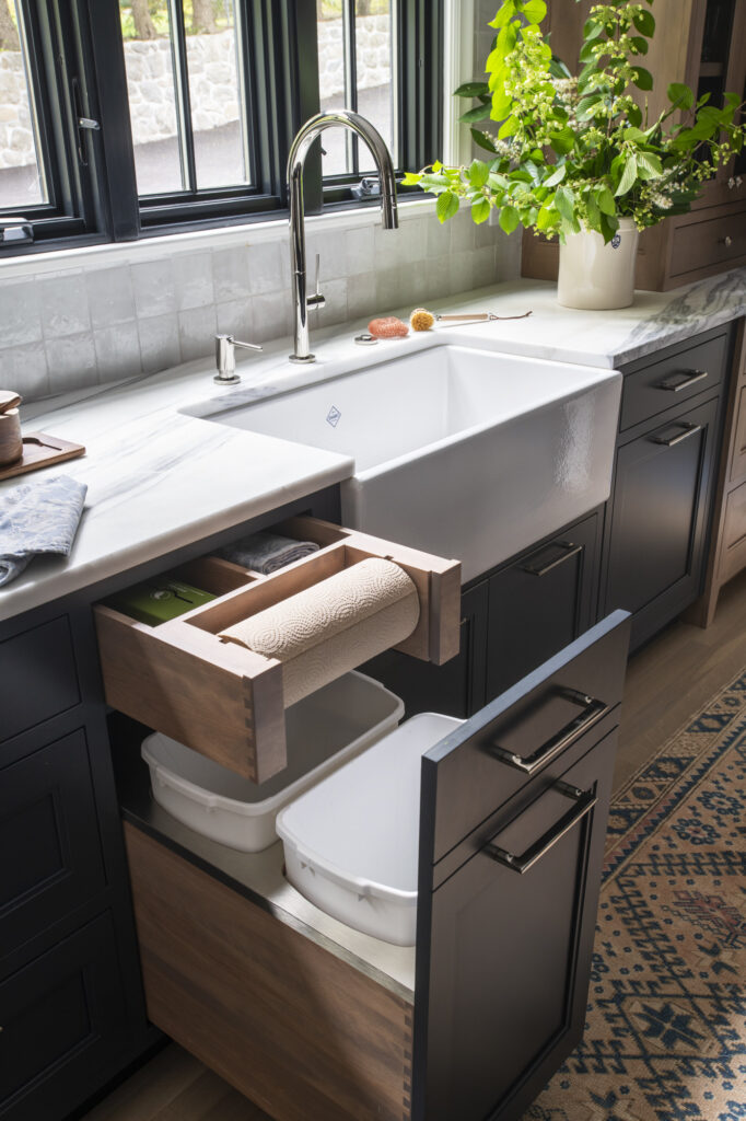 sink area with pull out garbage cans and paper towel holder in kitchen